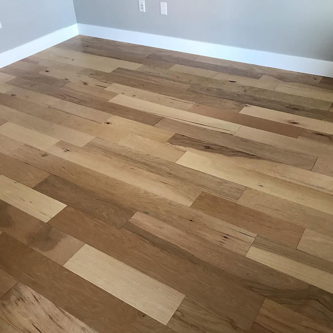 Mixed-tone hardwood floor across an empty room