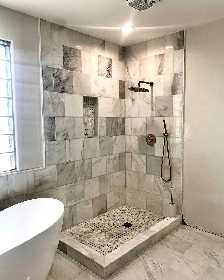 Marble-look walk-in shower with mosaic floor and recessed niche