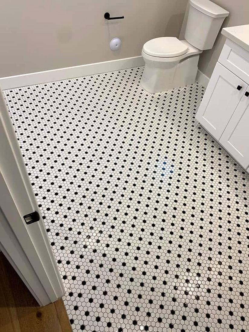 White hexagon tile floor with black dot accents in a bathroom
